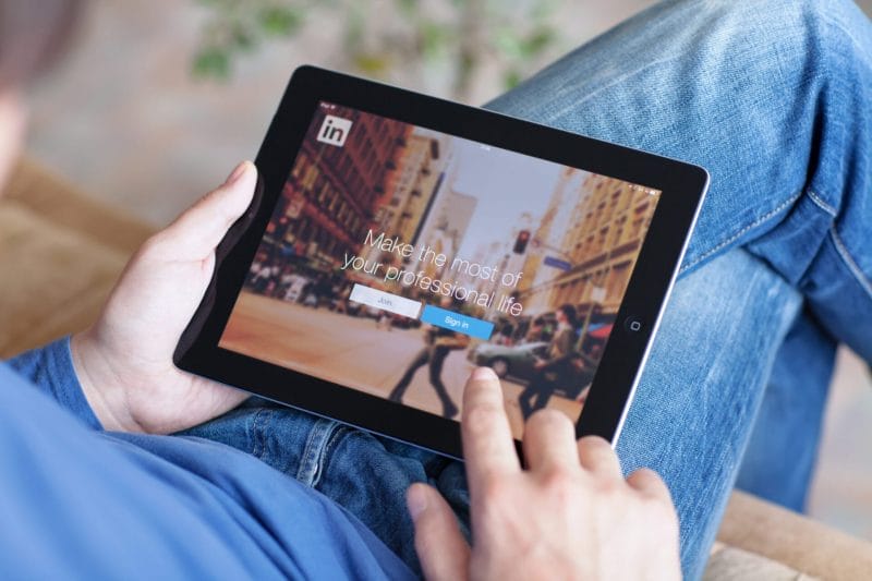 man holding ipad with app linkedin on the screen